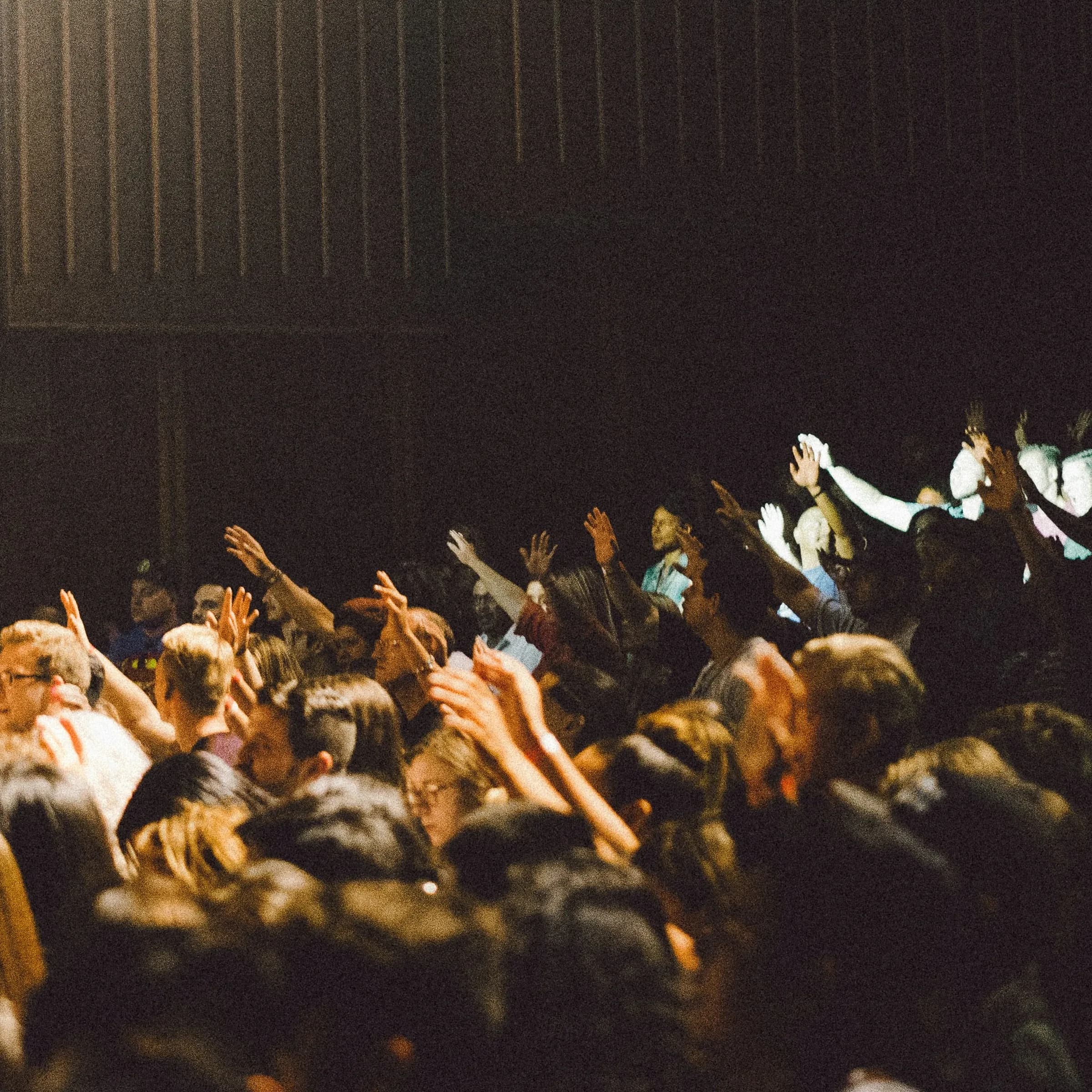 A full university lecture hall, hands raised